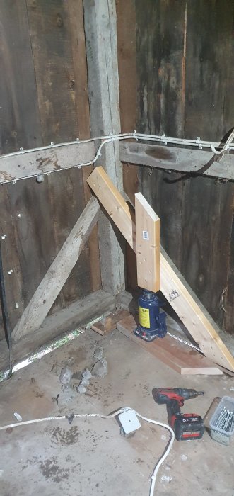 Pelardomkraft lyfter en träregel vid en vägg i renoveringsprojekt.