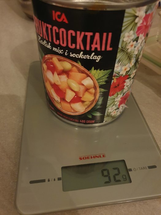 En fruktkonservburk på en digital köksvåg som visar 92 gram.