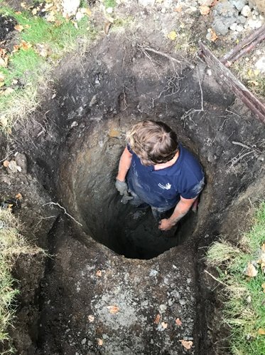 Person som gräver ett djupt hål i jorden för att utforska grundförhållandena på en blivande byggplats.