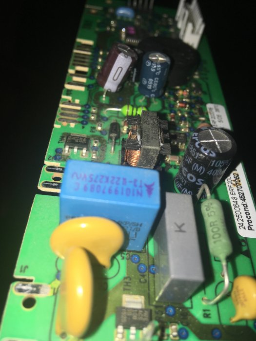 Elektroniskt kretskort med kondensatorer, resistanser och anslutningar i närbild.