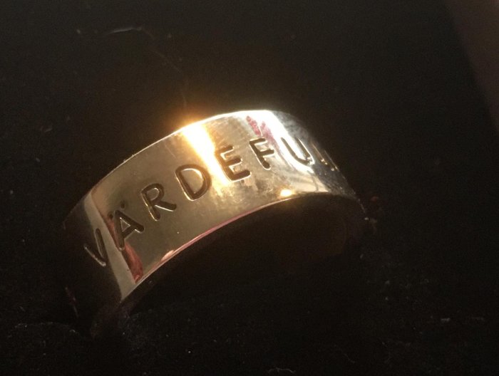 Silverring med svärtad inskription "VÄRDEFU", symboliserande början på frasen "Livet är värdefullt".