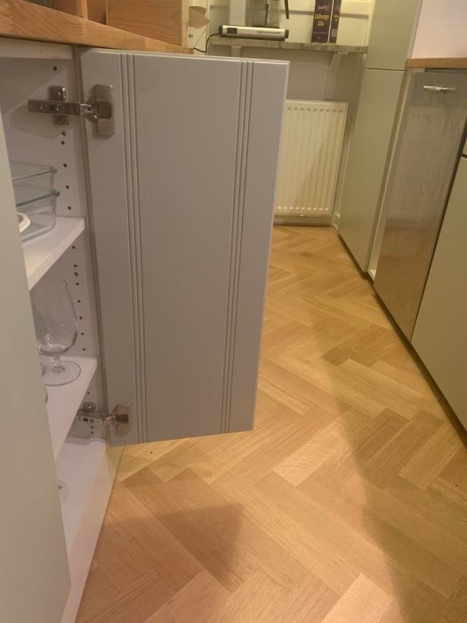 Renoverat kök med nymålade, gröna skåpluckor och parkettgolv.