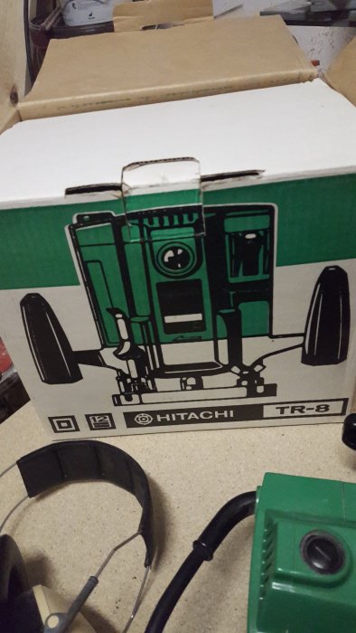 En Hitachi TR-8 handöverfräs ligger framför sin produktkartong med en illustration av handöverfräsen på.