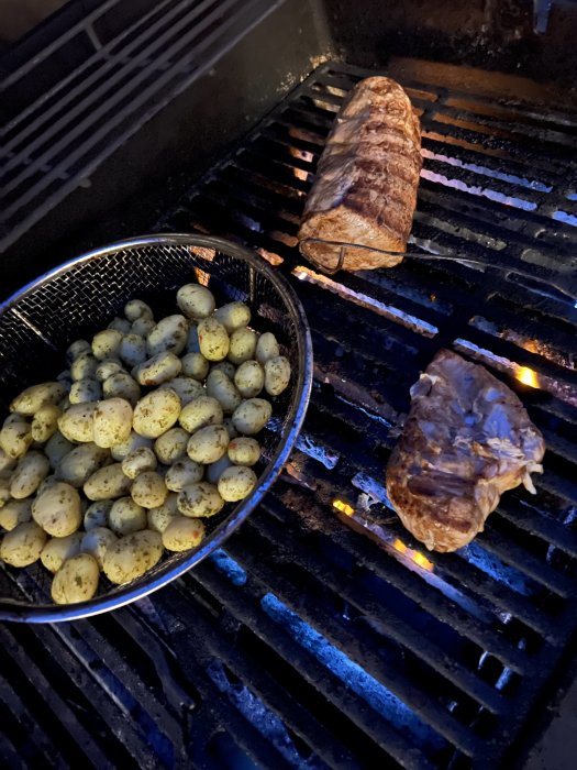 Grillat kött och kryddiga potatisar på en gasolgrill.