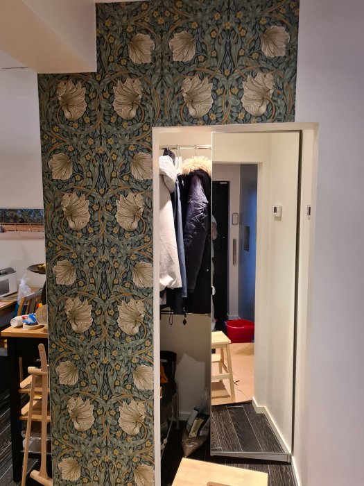 Hemmiljö med en nytapetserad pelare i William Morris-stil, en klädhängare och öppen dörr.