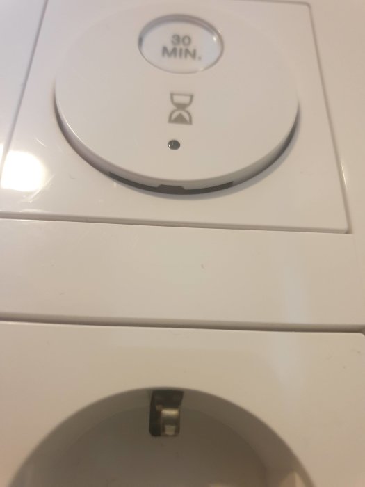 Timer från Schneider monterad på vägg med justeringsglugg synlig på undersidan.