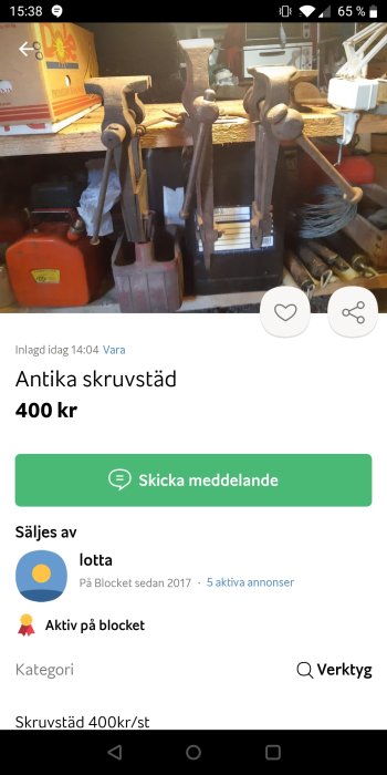 Tre antika skruvstäd av metall uppställda på en arbetsbänk till försäljning.