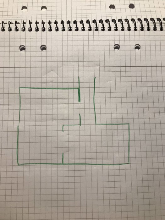 Handritad skiss av rumsutformning på rutat papper med markerat hörn för golvläggning.
