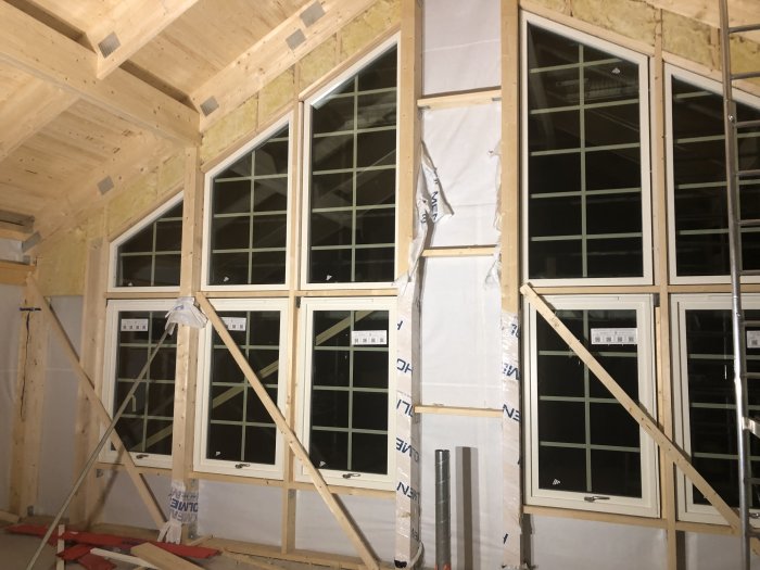 Nyligen installerade fönster i en byggnadsstomme med synlig isolering och vindskyddsduk.