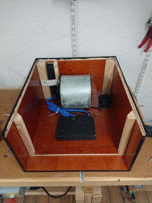 DIY luftrenare under konstruktion, öppen låda med fläktmotor och elektronik på arbetsbänk.