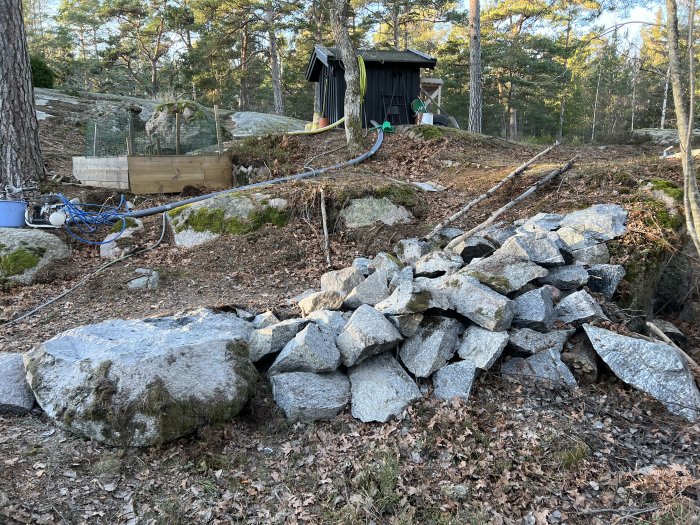 Spräckt sten och grus anlagd som en väg på en ojämn tomt med träd och en liten byggnad i bakgrunden.