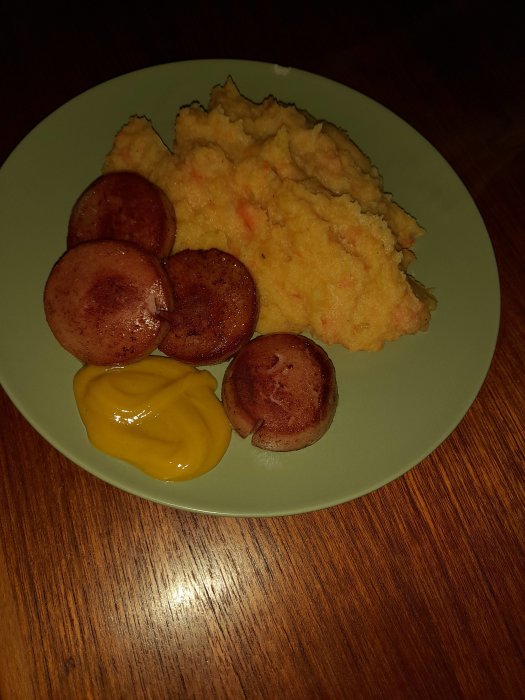 En tallrik med rotmos, stekta falukorvsskivor och senap.