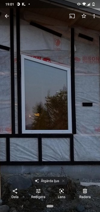 Fast PVC-fönster installerat i en isolerad husvägg under konstruktion.