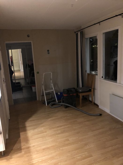 Kök under renovering med nakna gipsskivor, stege, arbetsmaterial och parkettgolv.