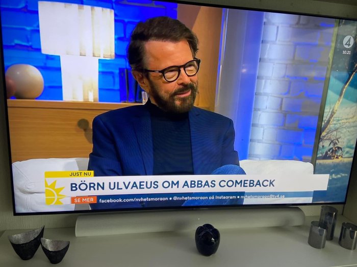 TV-skärm som visar intervju med en glad man, text på skärmen om Abba's comeback.