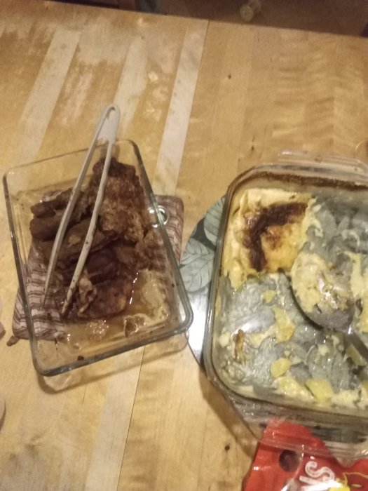 Två ugnsformar på ett träbord, en med fläskkotletter och en med potatisgratäng toppad med ost.