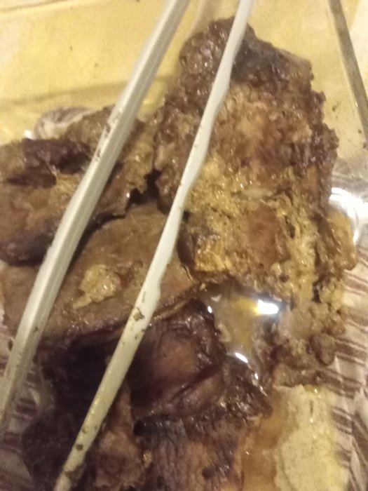 Långkokta fläskkotletter i gryta med soja och sambal oelek, serverade på tallrik.