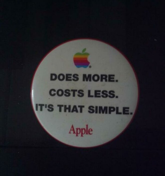 Rund dekal med texten "DOES MORE. COSTS LESS. IT'S THAT SIMPLE. Apple" och en regnbågsfärgad logotyp.