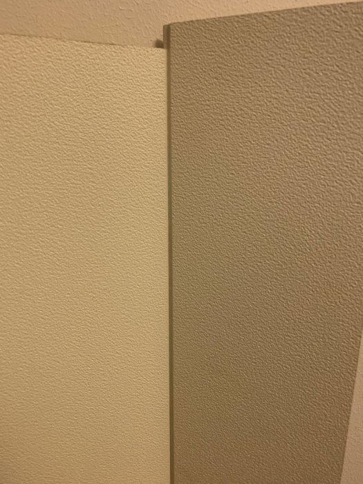 Två lösa takplattor placerade i vinkel mot varandra längs en vägg.