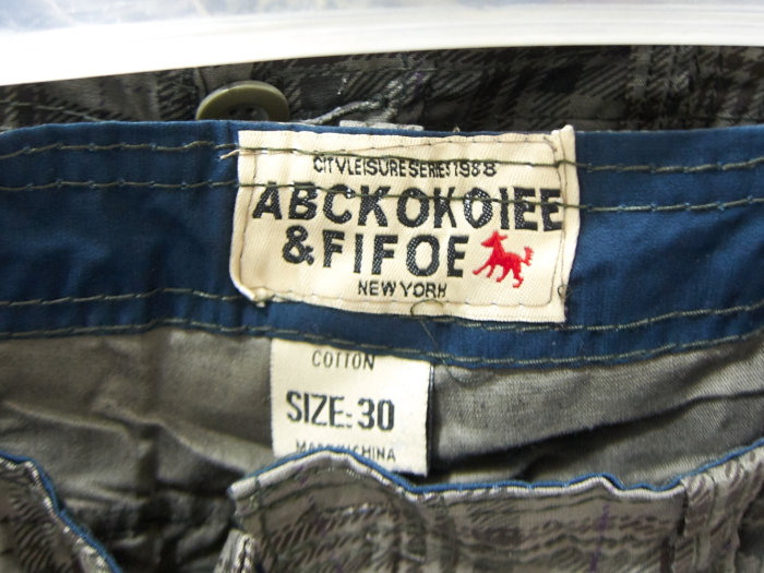 Märkeslogga på ett par jeans med texten 'ABCKOKOIEE & FIFOE' och röd figur, för att diskutera kvalitetsintryck.