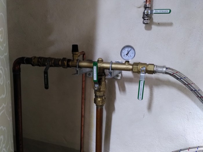 Vattenledningsfördelarrör med manometer och stängda ventiler under trycktest.