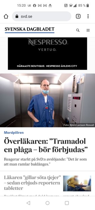 Man i blå sjukhusklädsel felaktigt bär ett munskydd under näsan i en hiss.
