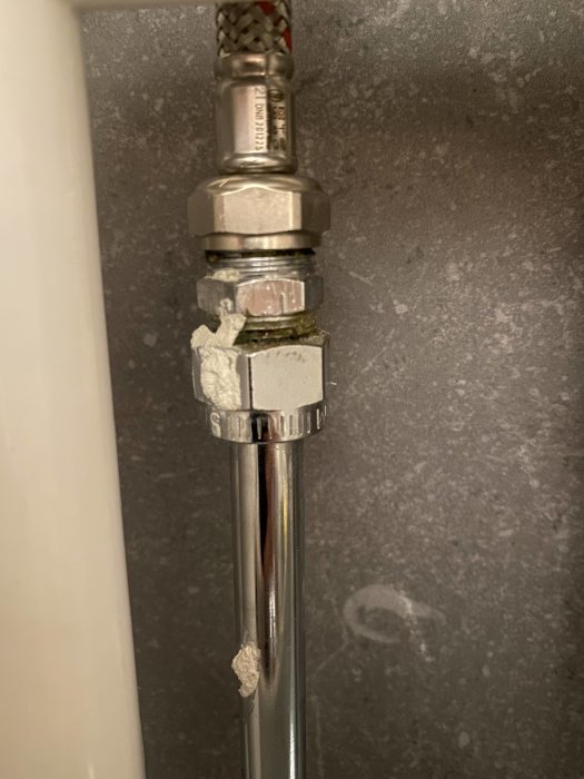 Spända vattenslangar till blandare med för korta anslutningar mot grå bakgrund.