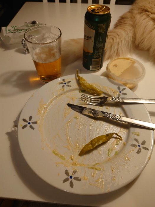 Ölburk och halvfullt glas bredvid en tallrik med matrester och en chili.