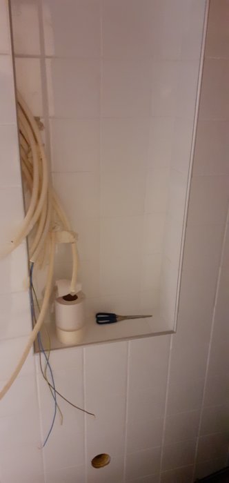 Installation av vattenburen värme med pex-rör, elledningar och golvbrunn i ett kaklat utrymme.