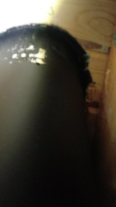 Mörk, otydlig bild av en persons silhuett i ett utrymme med träväggar.
