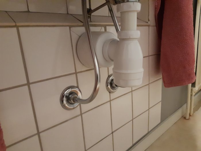 Vattenledningsrör och avloppsrör i en vägg med kakel under en badrumsrenovering.