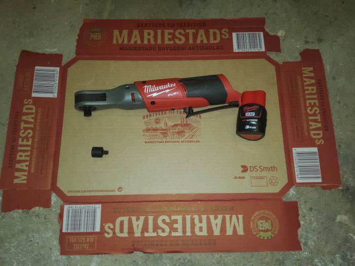 Milwaukee 3/8" mutterdragare och batteri på en Mariestads ölkartong.