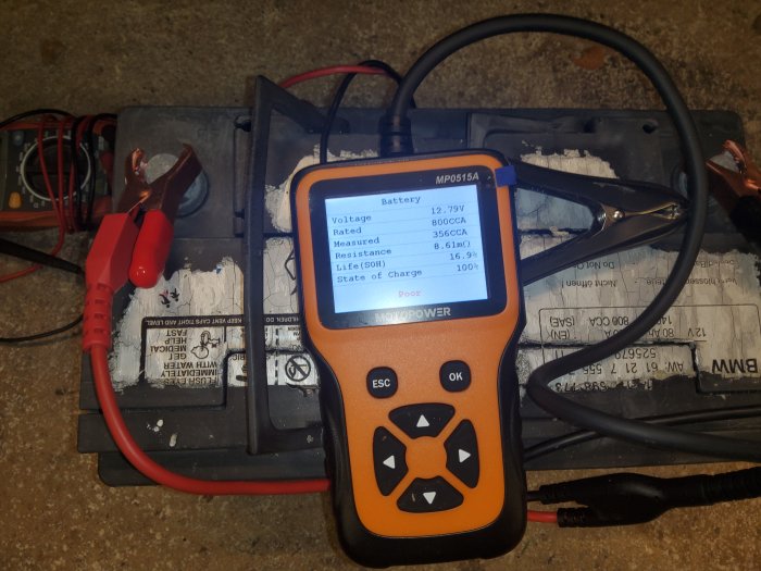 Batteritestare ansluten till ett bilbatteri med mätresultat på skärmen.