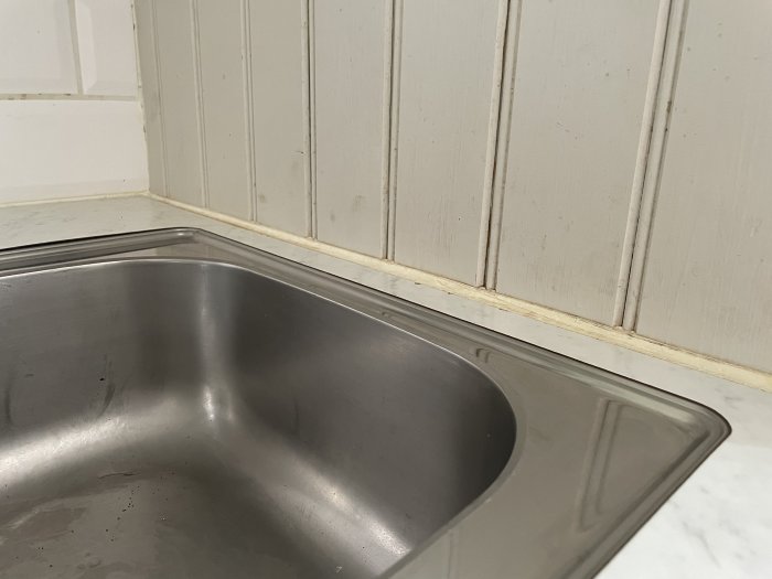 Infälld rostfri diskho vid träpanel och kakel, vill återanvändas vid köksrenovering.