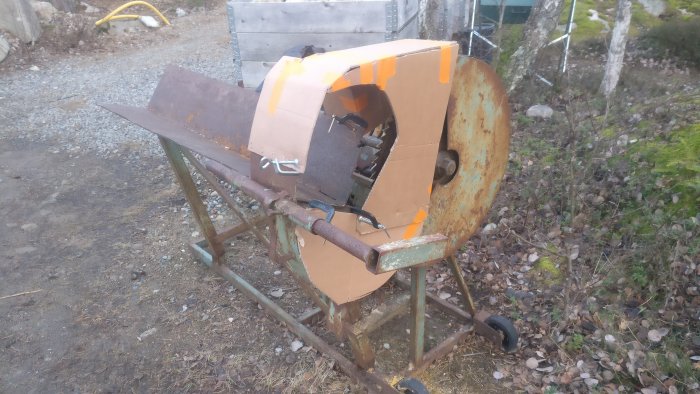 Prototyp av skydd till kapmaskin med brunt skydd av kartong, fasttejpad med orange tejp, utomhus.