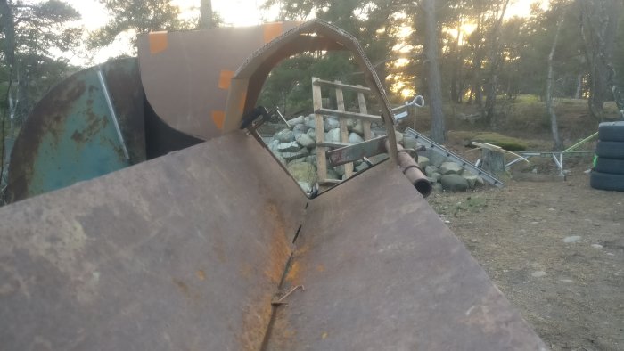Prototyp av en maskin med skydd och bortstyrande plåt under arbete i ett friluftsområde.