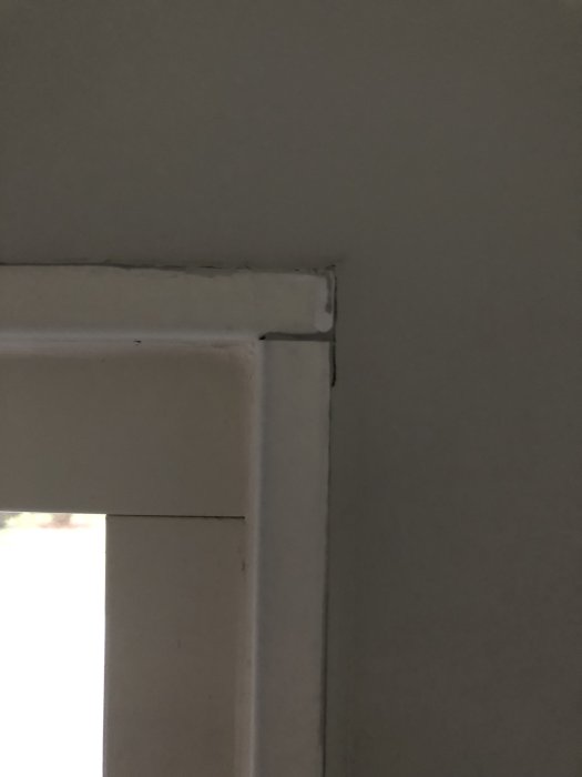 Ojämn och dåligt målad skarv längs en dörrkarm upp till taket.