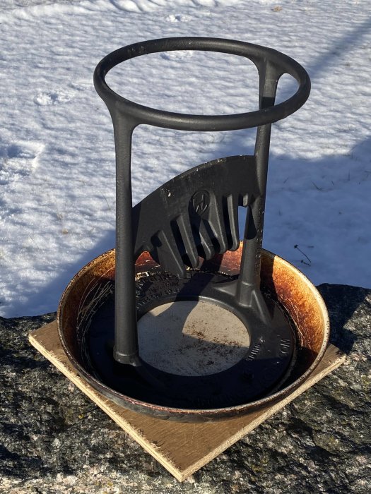 Kindling Cracker vedklyv placeras ovanpå en gammal stekpanna och en bit plywood på snötäckt mark.