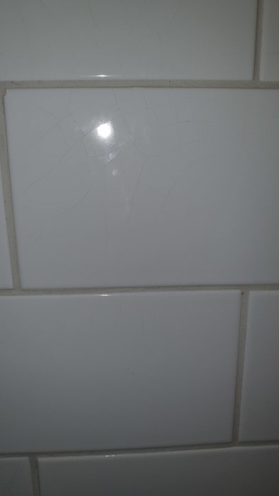Kakel med spindelnätsliknande sprickor i ett badrum som indikerar potentiell felaktig hantering av fix.