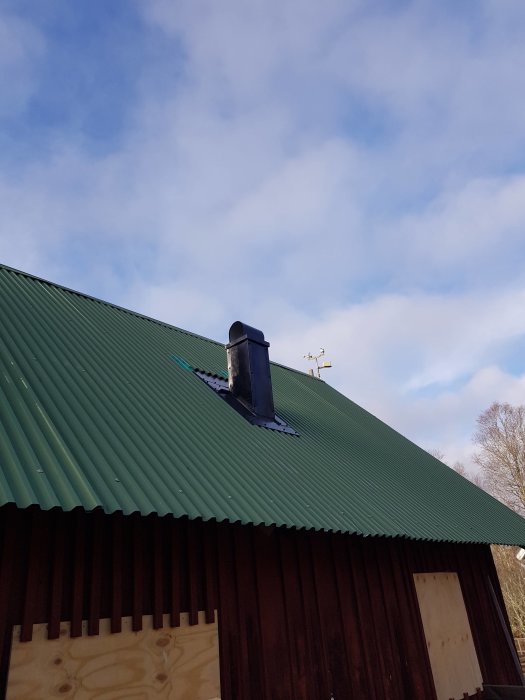 Nytillverkad plåthuv för ventilation över keramikugn på ett grönt tak, byggd av spillbitar av skorstenar.