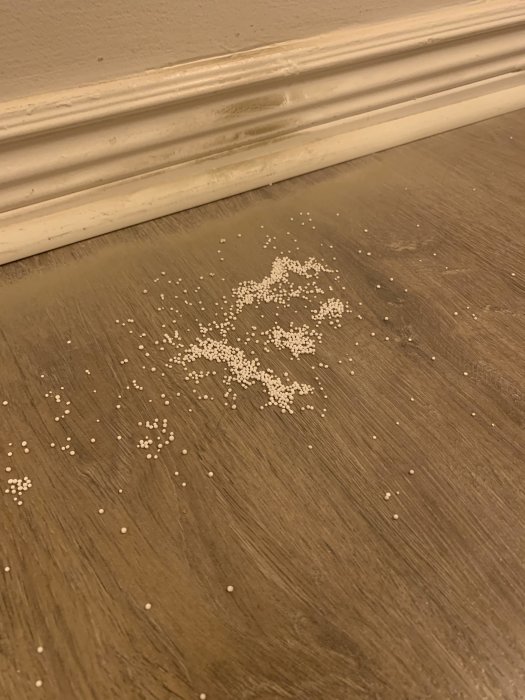 Vita kulor och svart damm vid golvsockeln i ett vardagsrum, tecken på sviktande golv.