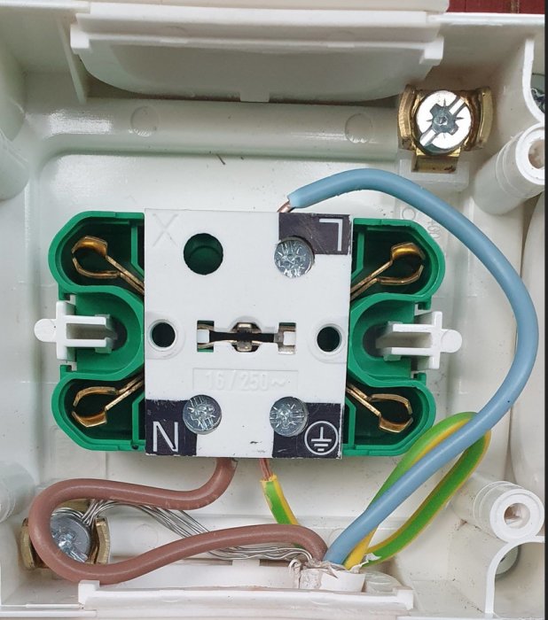 Elektrisk anslutning i en strömbrytare med synliga ledningar och kopplingsterminaler.