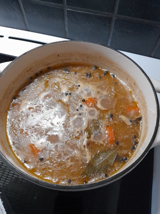 En gryta med kalops som tillagas, synliga bitar av kött och morötter samt lagerblad.