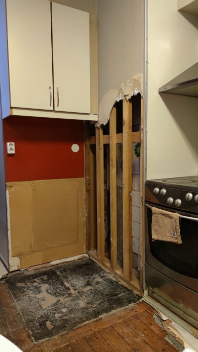 En renoverad hörna av ett kök med avlägsnat gips till synliga träreglar och isolering.