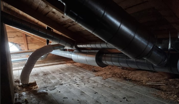 Ventilationssystem under installation på vind med rör och flexdämpare synligt.