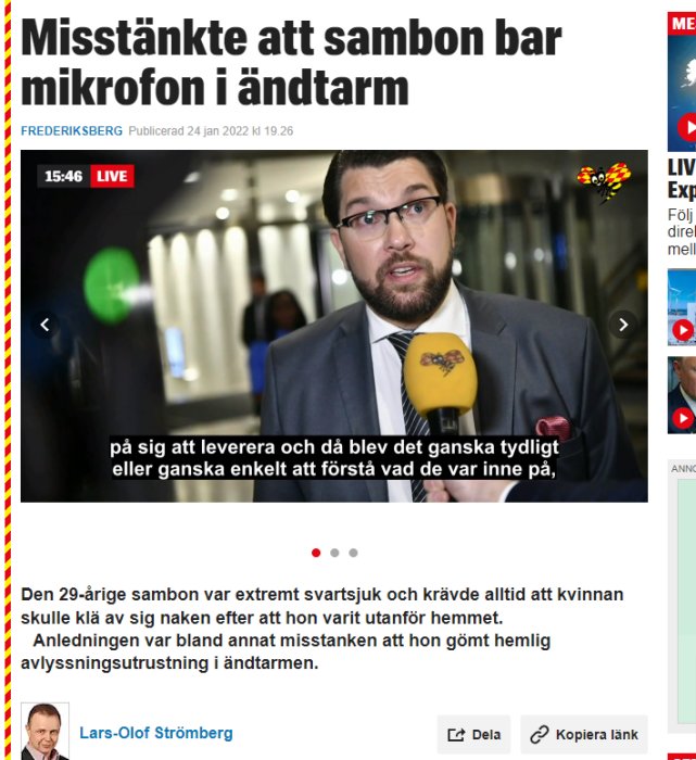 Man i kostym intervjuas av reportrar, håller en mikrofon med logotyp.