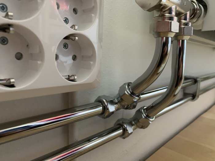 Parallellkopplade rör och termostatventil för radiator, med matning från vänster, under eluttag.