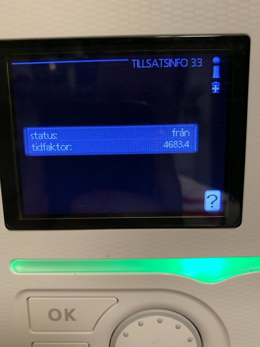 Skärm med text "TILLSATSINFO 33", status- och tidsinformation, och en grön lysdiod ovanför en OK-knapp.