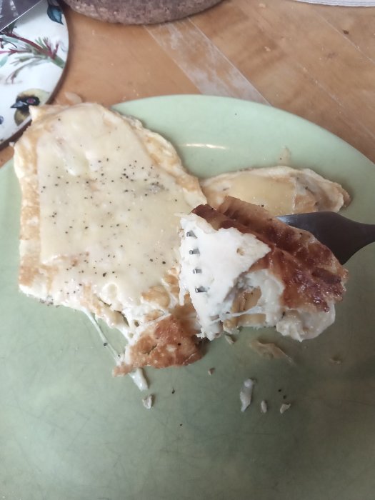 Halväten varm macka med ost, skinka och tomat på en grön tallrik.