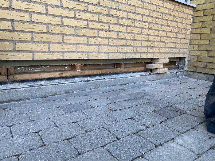 Delvis borttagen syll med exponerade bjälkar vid en husvägg under renovering.